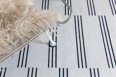 a white rug with black lines on it and a metal hook in the corner next to it