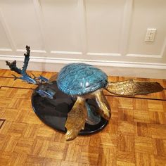 a blue turtle statue sitting on top of a wooden floor next to a white door