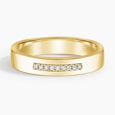 a yellow gold wedding band with channeled diamonds on the outside, set against a plain white background