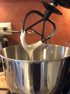 a large metal bowl on top of a stove with a whisk in it