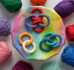 several balls of yarn and crochet rings on top of a colorful cloth covered in multi - colored yarn