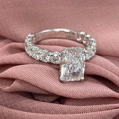 a diamond ring sitting on top of a pink cloth