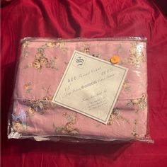 a pink sheet with flowers on it is wrapped in plastic and has a price tag