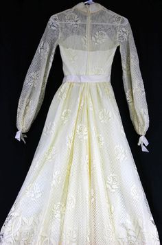 "Ivory dress, heavy-weight polyester lined with a cotton type of lace Grosgrain ribbon trim, sweetheart neckline under the lace. Ribbon around waist with long ribbon strands hanging from waist. Long sleeves with ribbon gathered cuffs. High neckline with dainty flower embroidered trim Train comes to a V like point On left-back arm seam, there is some lace stitching that has loose strands. Metal zipper closure No tags anywhere, appears to be handmade Woman's Size 6/8 based on measurements Approx m Spring Wedding Gown With Delicate Lace, White Lace Dress With Fitted Bodice And Lace Sleeves, Lace Dress For Garden Party, Spring Wedding Gown With Lace Trim, Fitted Cream Gown With Sweetheart Neckline, Cream Fitted Gown With Sweetheart Neckline, Fitted Lace Dress For Garden Party, Cream Lace Trim Dress With Sweetheart Neckline, Cream Dress With Lace Trim And Sweetheart Neckline