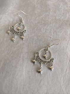 These gorgeous, dainty drop earrings feature filigree charms decorated with mini stars, like a night sky. Choose between silver or bronze! Dainty Silver Hoop Earrings For Party, Elegant Metal Earrings With Star Charm, Silver Star Charm Earrings, Silver Hoop Earrings With Star Charm For Party, Silver Dainty Star Charm Earrings, Silver Dainty Earrings With Star Charm, Silver Drop Earrings With Dangling Charms, Elegant Star-shaped Nickel-free Hoop Earrings, Bohemian Star-shaped Nickel-free Earrings