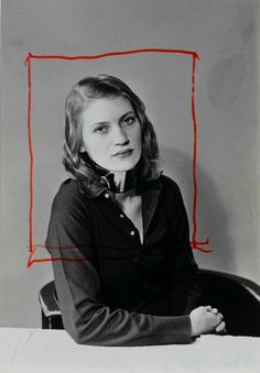 a woman sitting at a table in front of a red rectangle on the wall