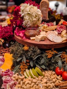 an assortment of cheeses, crackers and vegetables on a platter with flowers