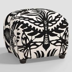 a black and white ottoman with an intricate design on the top, sitting in front of a gray background