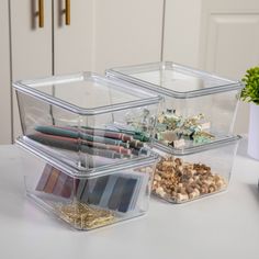 three plastic containers with different types of items in them on a table next to a potted plant