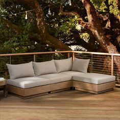 a couch sitting on top of a wooden deck next to a tree filled with leaves