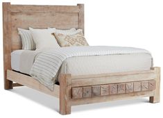 a wooden bed with white sheets and pillows