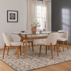 a dining room table with chairs and a rug on the floor in front of it