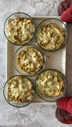 four glass dishes filled with food sitting on top of a white counter next to red yarn