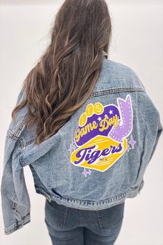 Officially licensed with Louisiana State University Rivalry Runway Denim Jackets make the perfect game day outfit and are the best gift for your favorite fan! Fit: Oversized Material: Denim (85% cotton, 15% polyester) Color: Medium/dark wash denim Care: Machine wash delicate cold & tumble dry low Casual Game Day Outerwear With Letter Print, Casual Outerwear With Letter Print For Game Day, Casual Letter Print Outerwear For Game Day, Game Day Cotton Outerwear With Letter Print, Collegiate Cotton Outerwear For Game Day, School Spirit Cotton Outerwear For Game Day, Casual Fall Outerwear For Fan Gear, Casual Spring Denim Jacket For College, Casual Cotton Denim Jacket For College