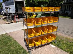 several yellow bins are stacked on top of each other in a metal rack outside