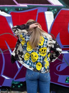 a woman standing in front of a graffiti wall with her back turned to the camera