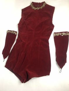 a red velvet dress with gold trimmings on the sleeves and cuffs is laying on a white surface