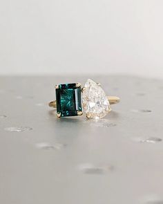 two engagement rings, one with an emerald and the other with a white topazte