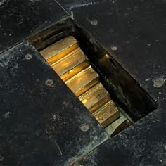 an open hole in the ground that is filled with metal bars and gold colored paint