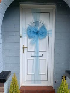 a white door with a blue bow hanging on it's side entrance to a house