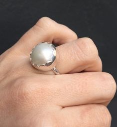 Choose your color and your ring size! This elegant and stately pearl ring is made from a beautiful and unique white cream 14mm Mabe South Sea AAA Pearl that has many hues including pink. The pearl has been set in sterling silver with a sterling silver ring band handmade from half dome wire. This ring has some height, the setting is almost 1/2 inch high. The white cream pearl is more matte than the other mabe pearls listed, but still has a luminescent quality that makes it captivating! Made to or Classic White Dome Ring For Wedding, Elegant Sterling Silver Cabochon Pearl Ring, Elegant White Pearl Ring With Round Band, Elegant White Pearl Ring, White Oval Dome Ring For Wedding, White Round Dome Ring For Anniversary, White Pearl Ring With Round Band For Formal Occasion, Formal White Pearl Ring With Round Band, Elegant White Moonstone Round Ring