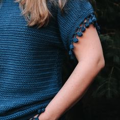 a woman wearing a blue knitted top with ruffles