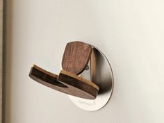 a wooden object is mounted to the wall by a metal hook on a white wall