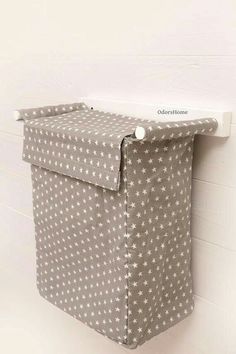 a gray and white polka dot storage bag hanging on the side of a brick wall