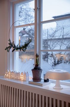 a window sill filled with candles next to a potted plant on top of a table