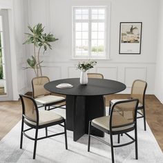 a black table with four chairs around it and a vase on the table in front of two windows