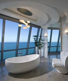 a large bath tub sitting in the middle of a bathroom next to a tall window