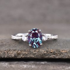 a blue and white diamond ring sitting on top of a stone