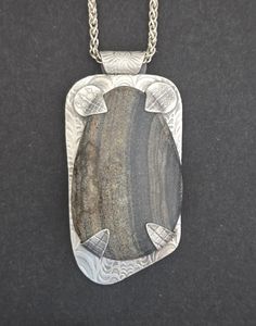 This piece began with a river rock from Big Creek, N.C. which was then hand-shaped and polished. The backplate,bail and tabs were hand-sculpted in fine silver metal clay and fired. The tabs and bail were torch fired to the backplate, which was polished, patina was added and it was polished again. Then the stone was hand-set. It measures 1 1/4" Wide by 2 5/8" Long by 1/2" Deep and comes on a 20" Sterling Silver Wheat Chain. Metal Clay Designs, Jewelry Metalsmithing, Metal Clay Art, Metal Jewelry Handmade, Metal Clay Tutorial, Kinetic Jewelry, Pmc Jewelry, Texture Jewelry, Patina Jewelry