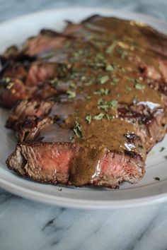 a steak covered in gravy on a white plate