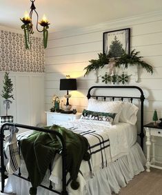 a bedroom with white walls and black iron bedspread, green throw pillows on the bed