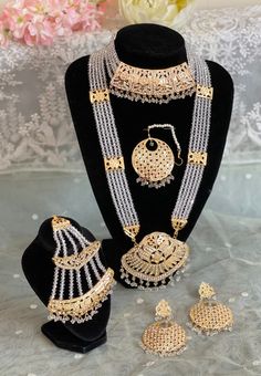 This beautiful Jadau bridal set comes complete with a choker, long haar, earrings, tika and side jhumar. With beautiful stone details on gold plating and white crystal beads this is a very elegant set that could be fashioned with a range of outfits. The set is lightweight so can be easily worn for long periods of time.  This eye catching unique ethnic jewellery set is ideal for any traditional attire  Wear this on saree , party wear on any festival or special occasions. This piece is readily available for immediate dispatch. Please note as this is a handmade piece there may be slight colour and texture variation due to lighting effects.  All sales are final. We do not offer a refund or exchange.  If you receive a damaged item please send a message with images of the damage.  Delivery avail Moti Jewellery Set, Moti Gold Set, Luxury White 22k Gold Kundan Necklace, Moti Sets Jewellery, Long Sets Gold Jewellery, Moti Set, Kundan Bridal Set, Saree Party, Unique Gold Jewelry Designs