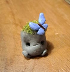 a small toy elephant with a blue flower on its head sitting on a wooden table