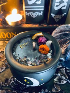 a pot filled with rocks and flowers on top of a table next to a lit candle