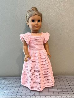 the doll is wearing a pink crocheted dress