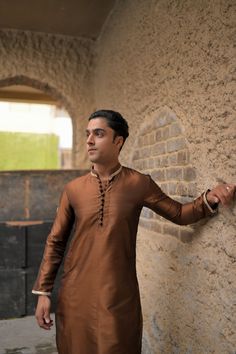 A brown silk kurta and fitted plain cotton silk pajama with gold embroidery on collar and sleeves and a matching motif on the arms, with round buttons to compliment the traditional look. Model wears a size Small. Gold Naqshi Straight Kurta, Brown Sets With Resham Embroidery And Long Sleeves, Brown Long Sleeve Sets With Resham Embroidery, Brown Fitted Long Sleeve Kurta, Brown Designer Wear Sets For Diwali, Bollywood Style Brown Sets For Eid, Brown Bollywood Sets For Eid, Eid Bollywood Brown Sets, Brown Bollywood Set For Eid