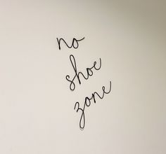 the word no shoe zone is written in cursive writing on a white wall