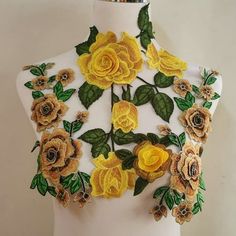 a white mannequin with yellow flowers and green leaves on it's back