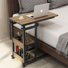 a laptop computer sitting on top of a wooden table next to a bed with pillows