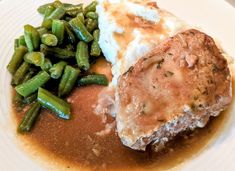 a white plate topped with meat, mashed potatoes and green beans