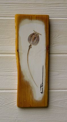 a piece of wood with a flower painted on it's side, hanging on the wall