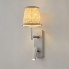 a white wall light with a fabric shade on it's side and a plugged in outlet