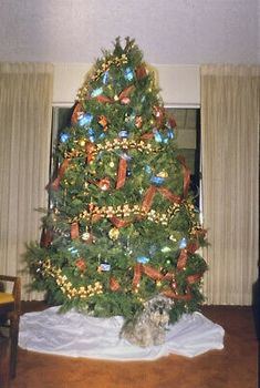 a christmas tree with presents on it and a dog sitting in front of the tree