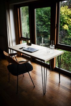 a table with a laptop on it next to a window