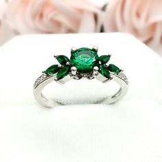 This beautiful ring is made from genuine 925 sterling silver with rhodium plating. Ring details- -The Main stone is a round cut 6mm Lab Created Emerald Stone -Side stones are 4mm by 2mm Lab Emerald Marquise and 1mm Round simulated diamonds -Ring is casted in solid 925 sterling silver with rhodium plating (yellow gold and rose gold plated also available, please check the drop down menu for more options) -The Total face height of the ring measures 7mms and the band width measures 1.5mms -Each ring Round Emerald Ring, Peridot Engagement Rings, Simulated Diamond Rings, Art Deco Diamond Rings, Ring Emerald, Diamonds Ring, Peridot Ring, Emerald Stone, Green Emerald