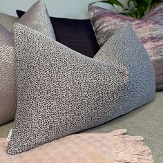 several pillows on a couch with a plant in the background